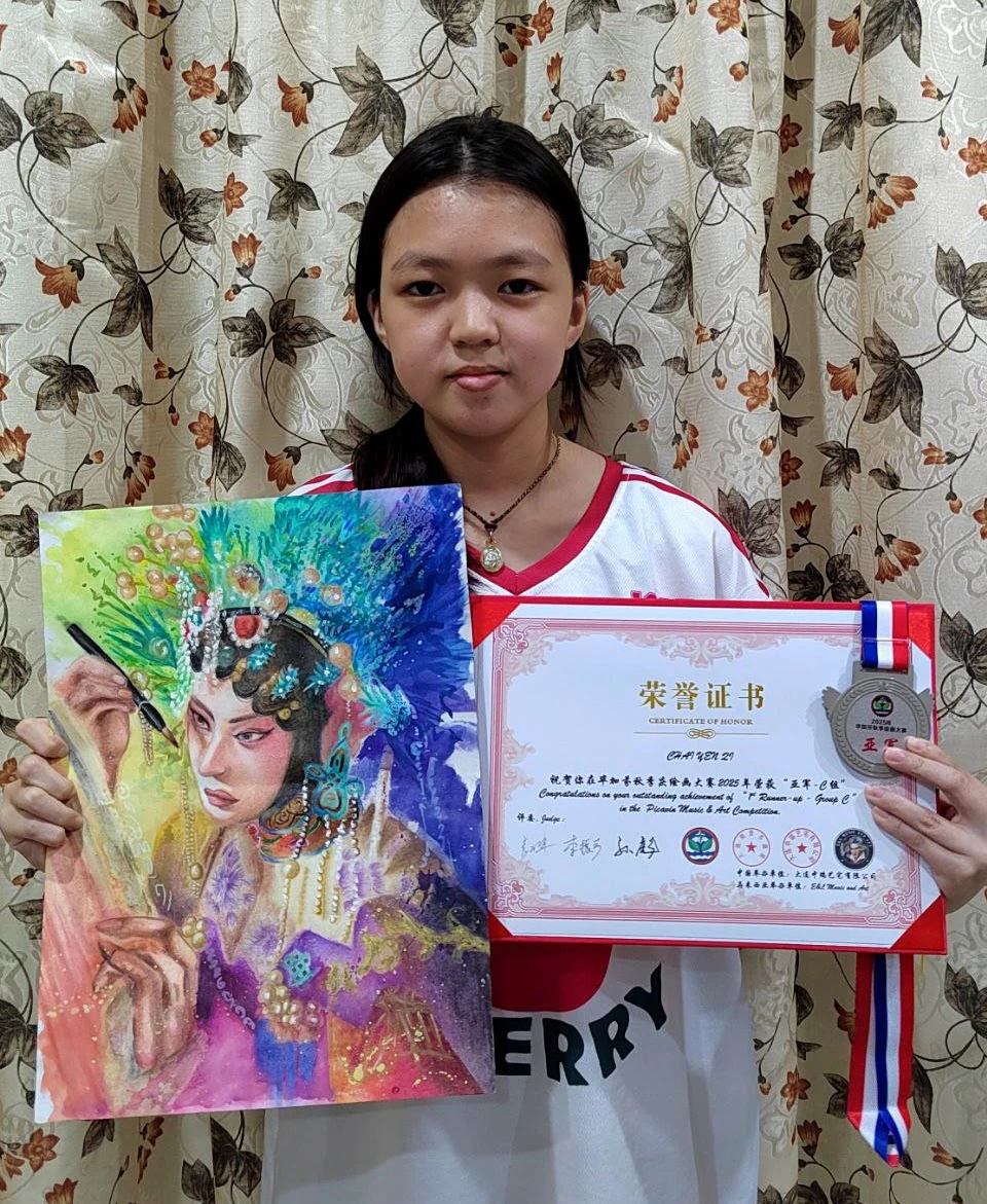 Student displaying a colourful portrait artwork and certificate