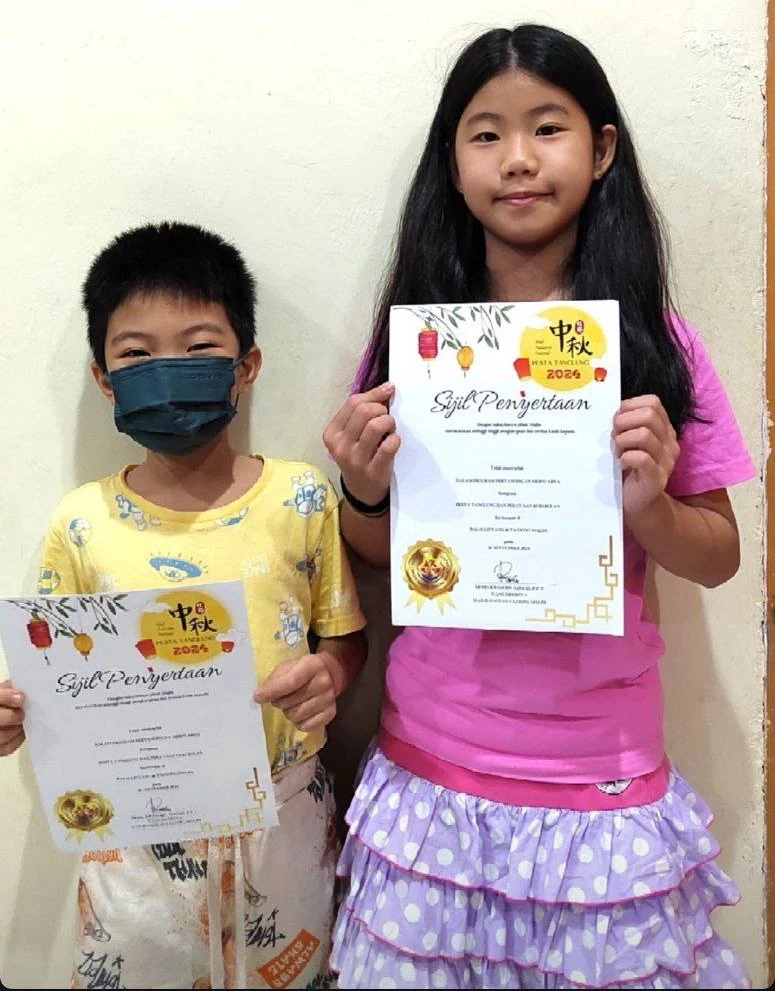 Two students displaying colourful achievement certificates