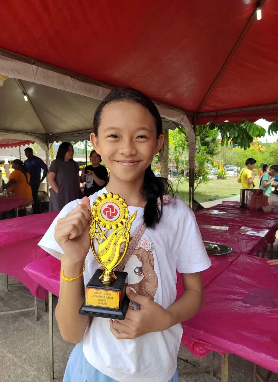 Student proudly holding an achievement trophy
