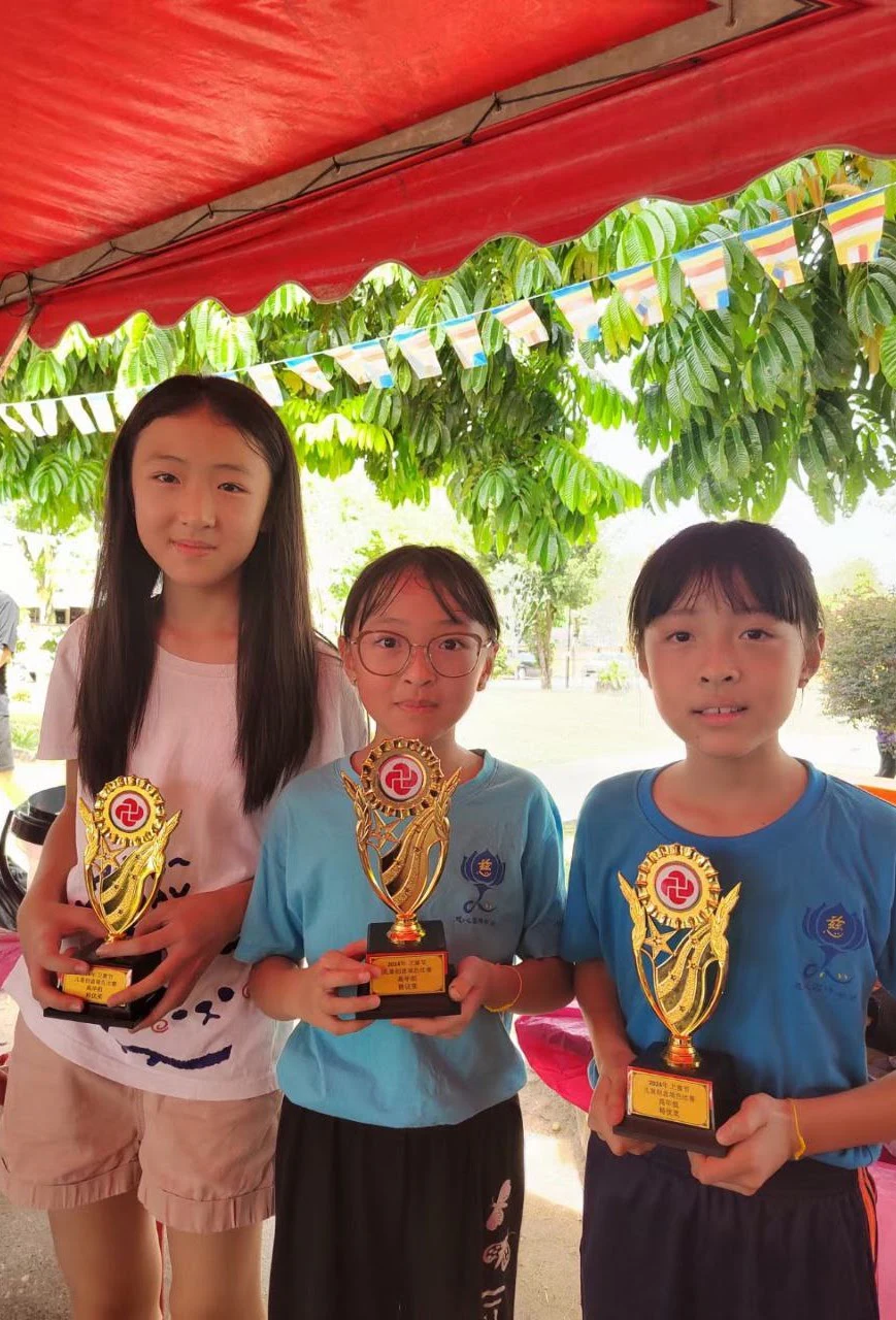 Three students standing together with achievement trophies