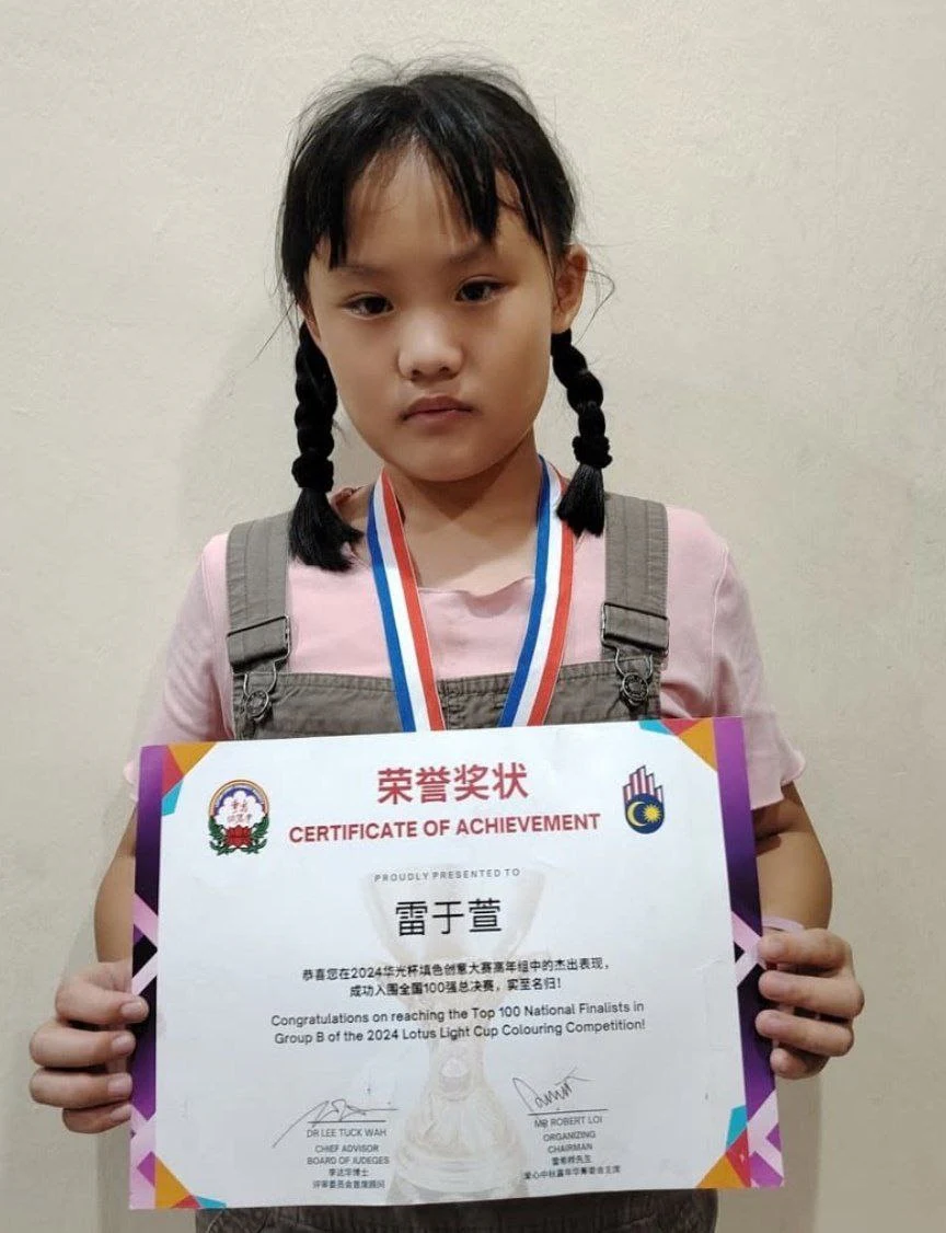 Student displaying a medal and achievement certificate