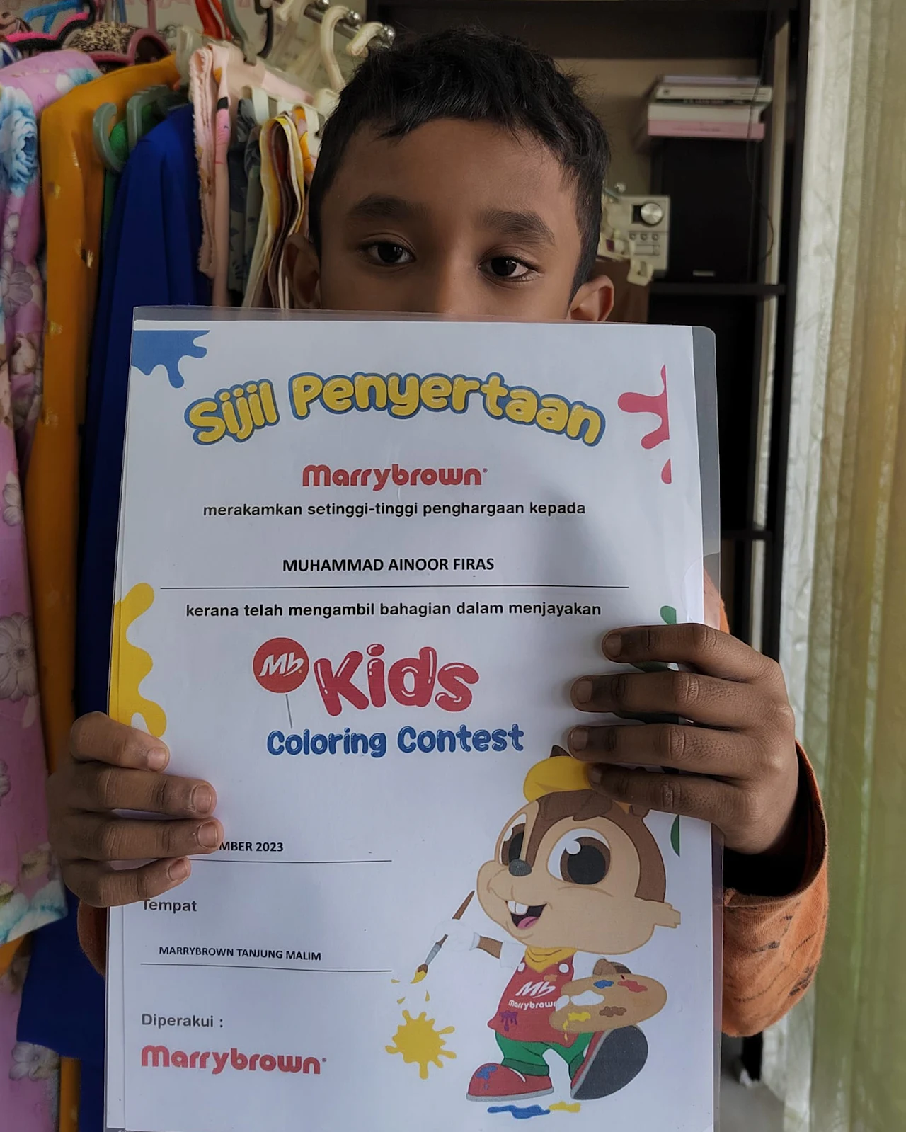 Student holding a colouring contest certificate
