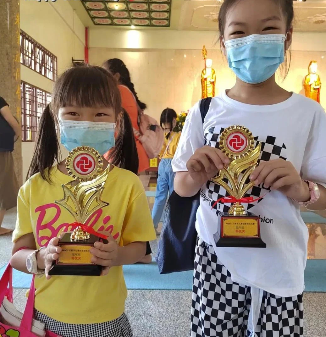 Two students displaying achievement trophies