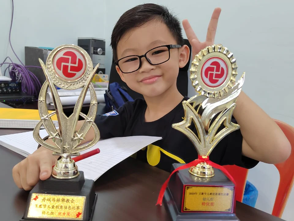 Student proudly displaying two achievement trophies