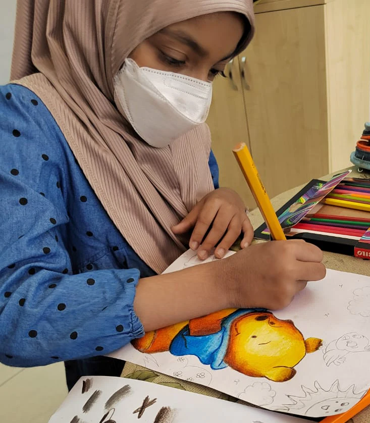 Student adding coloured-pencil details to a duck illustration