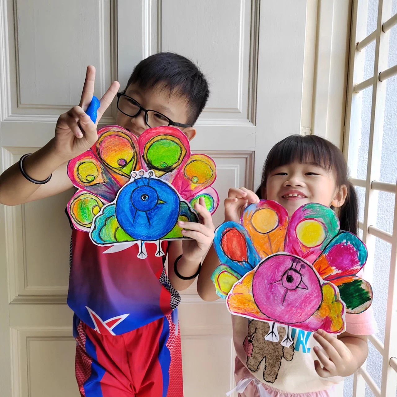 Two students displaying colourful layered flower crafts