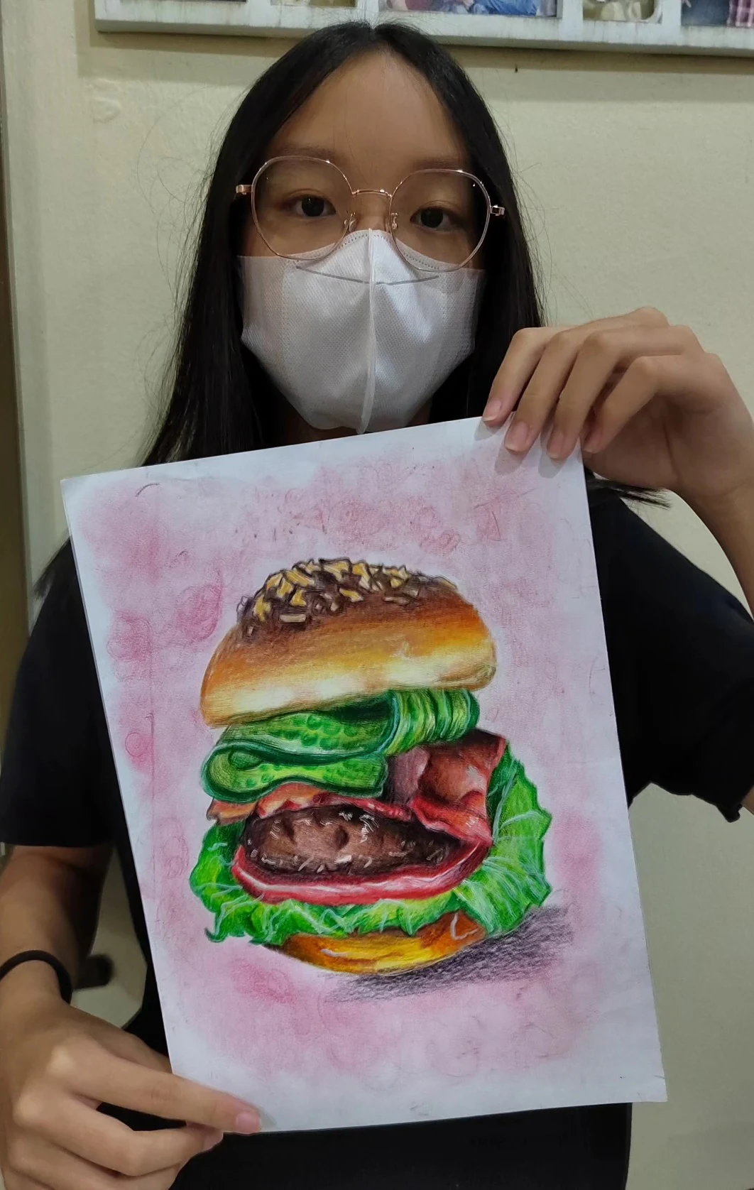 Student holding a brightly rendered burger drawing